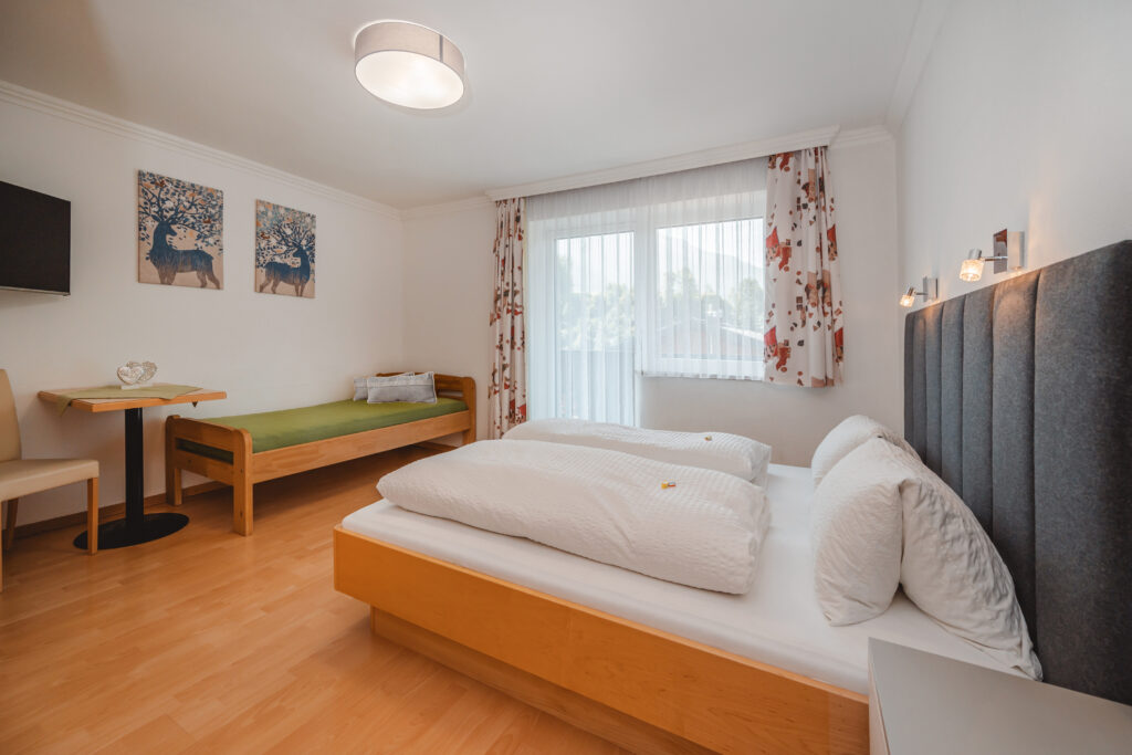 Appartement Grafenberg 1 - Schlafraum 1 mit Doppelbett, zusätzlichen Einzelbett, Flat TV und Balkon mit Blick auf Wagrain