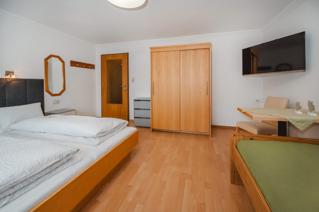 Appartement Grafenberg 1 - Schlafraum 1 mit Doppelbett, zusätzlichen Einzelbett, Flat TV und Balkon mit Blick auf Wagrain